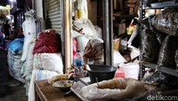 Seorang pedagang menunggu pembeli dengan duduk di samping dagangannya.  