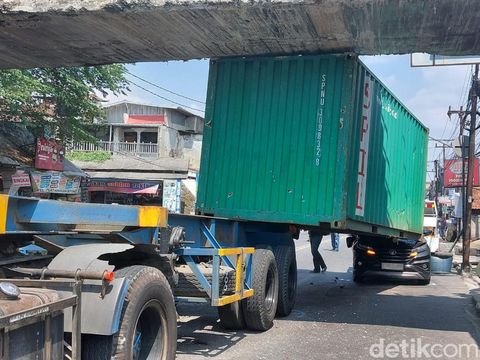 Truk membawa kontainer tersangkut jembatan terjadi di Kota Bogor, Jabar. Kontainer yang dibawa truk tersebut meniban mobil yang melaju di belakangnya. (M Sholihin/detikcom)