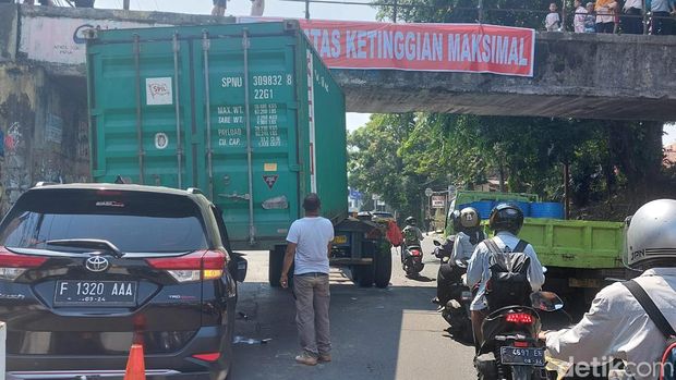 Truk membawa kontainer tersangkut jembatan terjadi di Kota Bogor, Jabar. Kontainer yang dibawa truk tersebut meniban mobil yang melaju di belakangnya. (M Sholihin/detikcom)