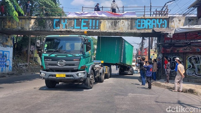 Truk membawa kontainer tersangkut jembatan terjadi di Kota Bogor, Jabar. Kontainer yang dibawa truk tersebut meniban mobil yang melaju di belakangnya. (M Sholihin/detikcom) Truk membawa kontainer tersangkut jembatan terjadi di Kota Bogor, Jabar. Kontainer yang dibawa truk tersebut meniban mobil yang melaju di belakangnya. (M Sholihin/detikcom)