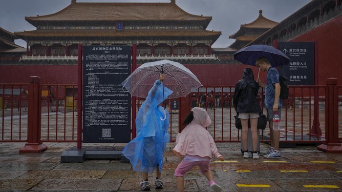 Wisata di Beijing Tutup Gegara Topan Doksuri Visitors covered up with umbrellas and rain covers gather at a closed Palace Museum store near the closed Forbidden City as a rainstorm soak Beijing, Sunday, July 30, 2023. Forbidden City and other tourist destinations in the capital city was ordered to close after authorities issued a red alert for rainstorms, as heavy rains brought by Typhoon Doksuri are expected to pound the Chinese capital and vast areas in the north. (AP Photo/Andy Wong)