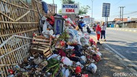Dua orang warga melintas di samping tumpukan sampah di Jalan Diponegoro KM 38 Jatimulya, Tambun Selatan.