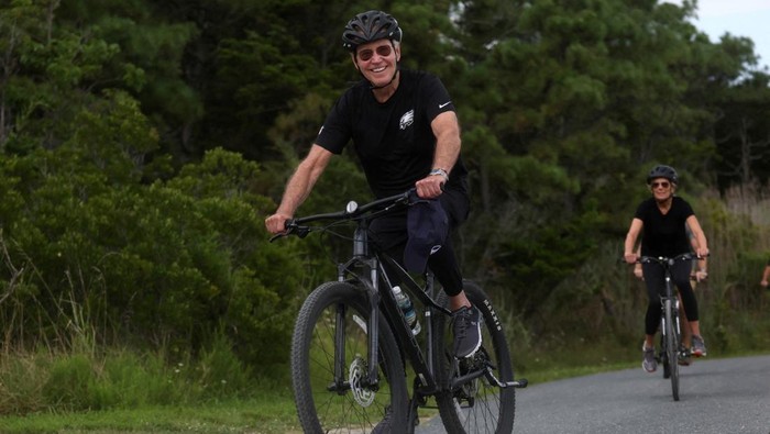 Momen Presiden Joe Biden Gowes Santai Saat Liburan di Pantai U.S. President Joe Biden and first lady Jill Biden ride bikes down a path in Gordons Pond State Park in Rehoboth Beach, Delaware, U.S., July 31, 2023. REUTERS/Leah Millis