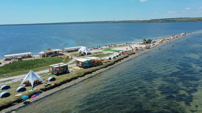 People rest on a narrow beach of the Tylihul river that widens into a broad estuary, amid Russia's attack on Ukraine, in Mykolaiv region, Ukraine July 29, 2023. REUTERS/Viktoria Lakezina