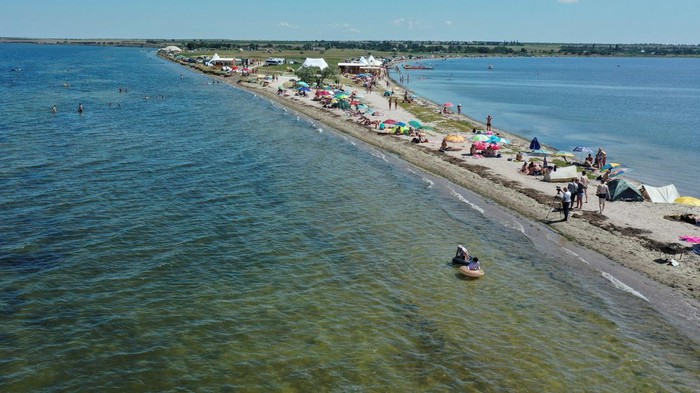 People rest on a narrow beach of the Tylihul river that widens into a broad estuary, amid Russia's attack on Ukraine, in Mykolaiv region, Ukraine July 29, 2023. REUTERS/Viktoria Lakezina