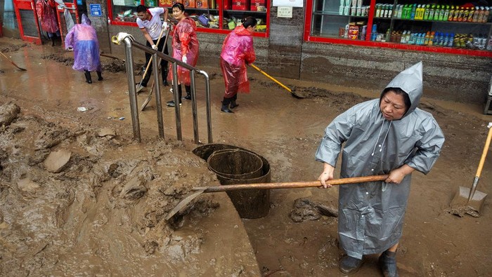 Banjir menyisakan material lumpur di sejumlah jalan di Beijing, China, Selasa (1/8/2023). Warga pun mulai membersihkan lumpur yang menyelimuti jalanan tersebut.