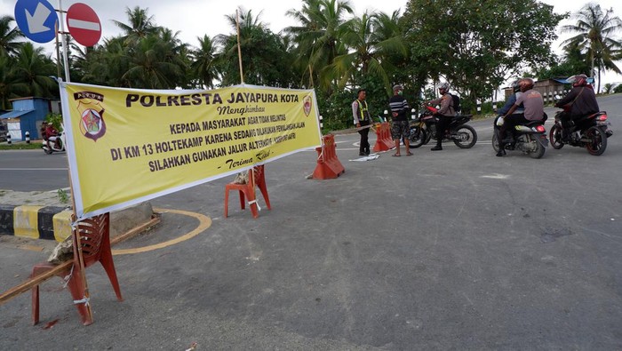 Aksi tutup jalan di Papua Warga melintas di dekat batang pohon kelapa yang melintang di KM 13 Jalan Holtekamp, Kota Jayapura, Papua, Rabu (2/8/2023). Menurut warga setempat penutupan jalan menggunakan pohon kelapa tersebut sebagai upaya warga meminta ganti rugi tanah ulayat mereka yang dijadikan jalan ke Pemprov Papua. ANTARA FOTO/Sakti Karuru/aww.