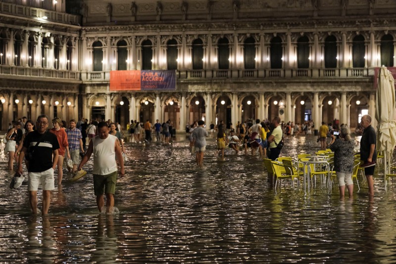 Tourists walk through flooded St Mark's Square after unusually high water levels in Venice, Italy, August 1, 2023. REUTERS/Manuel Silvestri