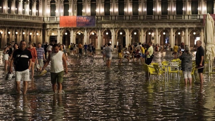 Tourists walk through flooded St Mark's Square after unusually high water levels in Venice, Italy, August 1, 2023. REUTERS/Manuel Silvestri