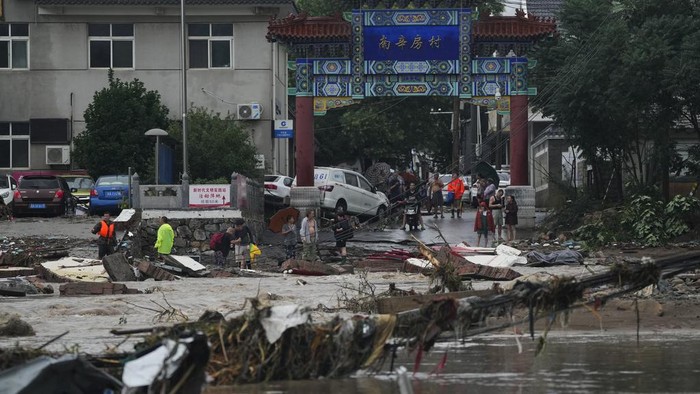 Beijing Porak-poranda Diterjang Topan dan Banjir Villagers gather near a collapsed road damaged by floodwaters in the Mentougou District as continuous rain fall triggers alerts in Beijing, Monday, July 31, 2023. (AP Photo/Andy Wong)