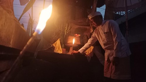 Bendesa Adat Tunjuk I Made Nawa memasang linting yang dibakar di merajan atau pura keluarga dan penjor di depan rumah saat Galungan, Rabu (2/8/2023).