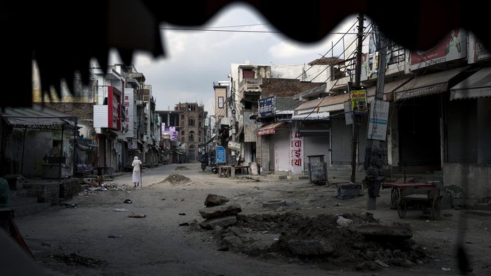 Broken glass and debris are strewn on a street as policemen patrol after communal clashes in Nuh in Haryana state, India, Tuesday, Aug., 1, 2023. Deadly clashes between Hindus and Muslims began in the area Monday afternoon during a religious procession by a Hindu nationalist group forcing Indian authorities to impose a curfew and suspend Internet services. (AP Photo/Altaf Qadri)