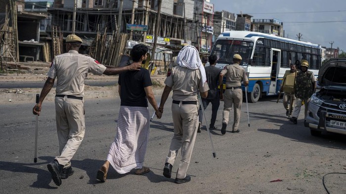 Broken glass and debris are strewn on a street as policemen patrol after communal clashes in Nuh in Haryana state, India, Tuesday, Aug., 1, 2023. Deadly clashes between Hindus and Muslims began in the area Monday afternoon during a religious procession by a Hindu nationalist group forcing Indian authorities to impose a curfew and suspend Internet services. (AP Photo/Altaf Qadri)