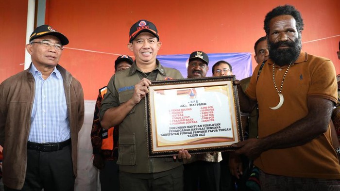 Kepala BNPB Letjen TNI Suharyanto (tengah) didampingi Menko PMK Muhadjir Effendy (kiri) menyerahkan bantuan kepada warga di Puncak, Papua Tengah.