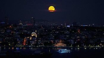 Supermoon terbit di langit saat kapal feri dan kargo melintasi Bosphorus di Istanbul, Turki, Selasa (1/8/2023). (AP Photo/Francisco Seco)