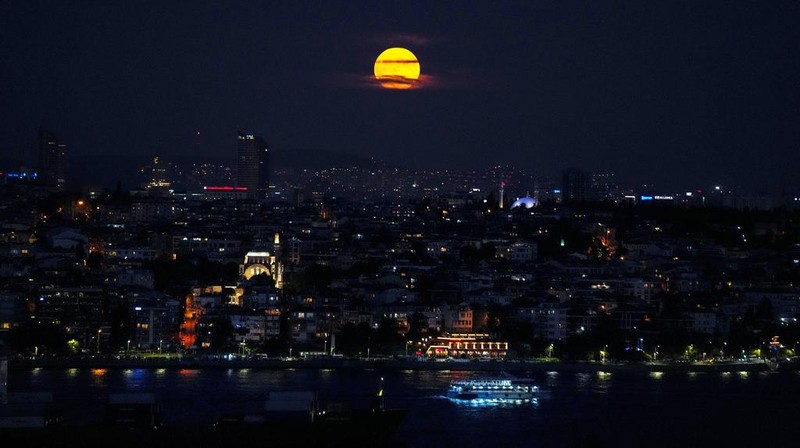 The supermoon rises in the sky as ferries and cargo ships cross the Bosphorus in Istanbul, Turkey, Tuesday, Aug. 1, 2023. The cosmos is offering up a double feature in August: a pair of supermoons culminating in a rare blue moon. (AP Photo/Francisco Seco)