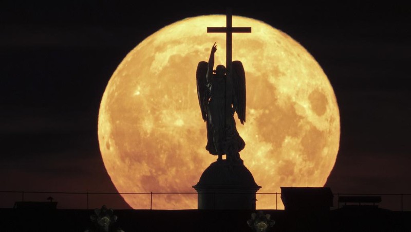 The supermoon rises behind a statue of an angel fixed atop the Alexander Column at the Palace Square in St. Petersburg, Russia, Tuesday, Aug. 1, 2023. (AP Photo/Dmitri Lovetsky)