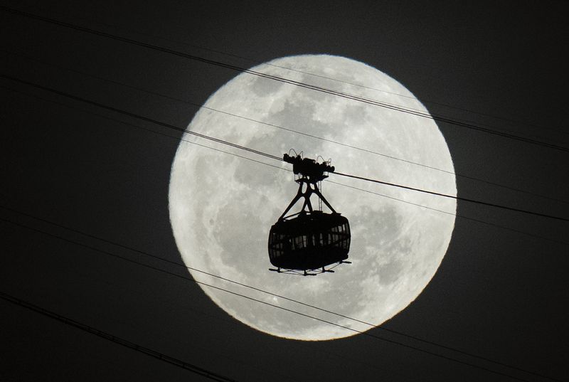 A cable car moves towards Sugar Loaf mountain as a supermoon rises on the night sky in Rio de Janeiro, Brazil, Tuesday, Aug 1, 2023. (AP Photo/Silvia Izquierdo)