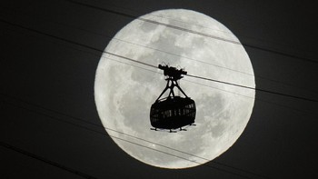 Kereta gantung bergerak menuju gunung Sugar Loaf saat supermoon terbit di langit malam di Rio de Janeiro, Brasil, Selasa (1/8/2023). (AP Photo/Silvia Izquierdo)