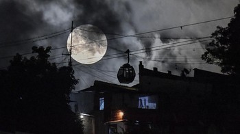 Sebuah kereta gantung bergerak menuju lingkungan San Agustin saat supermoon terbit di langit Caracas, Venezuela, Selasa (1/8/2023). (AP Photo/Matias Delacroix)