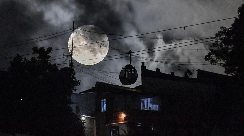 A cable car moves towards the San Agustin neighborhood as a supermoon rises in the sky of Caracas, Venezuela, Tuesday, Aug. 1, 2023. (AP Photo/Matias Delacroix)