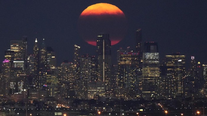 Pesona Supermoon di Atas Cakrawala Kota Manhattan The moon rises through clouds over the skyline of lower Manhattan as seen from West Orange, N.J., Tuesday, Aug. 1, 2023. The first of two supermoons in August graced the skies on Tuesday. A supermoon is broadly defined as a full moon that is closer to the Earth than normal. That makes it appear slightly brighter and bigger in the sky. (AP Photo/Seth Wenig)