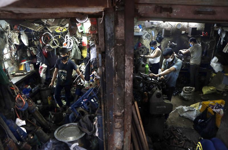 FILE - In this Friday, Sept. 25, 2020 file photo, people work in a workshop at Dharavi, one of Asia's largest slums, in Mumbai, India. Up to 150 million people could slip into extreme poverty, living on less than $1.90 a day, by late next year depending on how badly economies shrink during the COVID-19 pandemic, the World Bank said Wednesday, Oct. 7, 2020 in an outlook grimmer than before. (AP Photo/Rajanish Kakade, File)