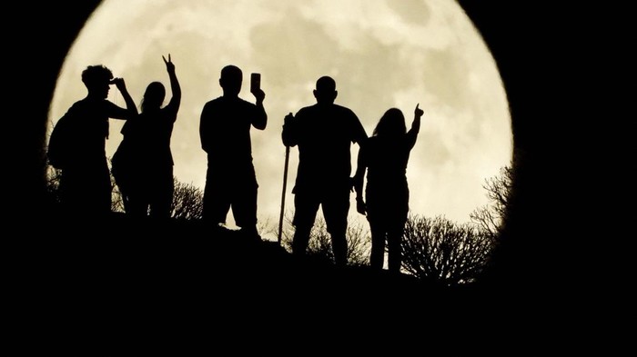 A family stand with the full moon known as the 