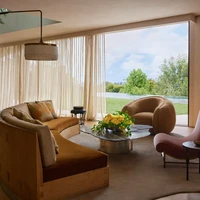 Interior rumah mengawinkan gaya retro dan modern dalam palet alam yang menciptakan atmosfer hangat. “Bagi banyak orang, ruang tamu lebih seperti buat pamer dan mereka malah menghabiskan waktu di ruangan lain tapi kami cukup sering berada di ruang tamu,” ungkap John dalam video di YouTube Architectural Digest. (Foto: Dok. Architectural Digest/Yoshihiro Makino)