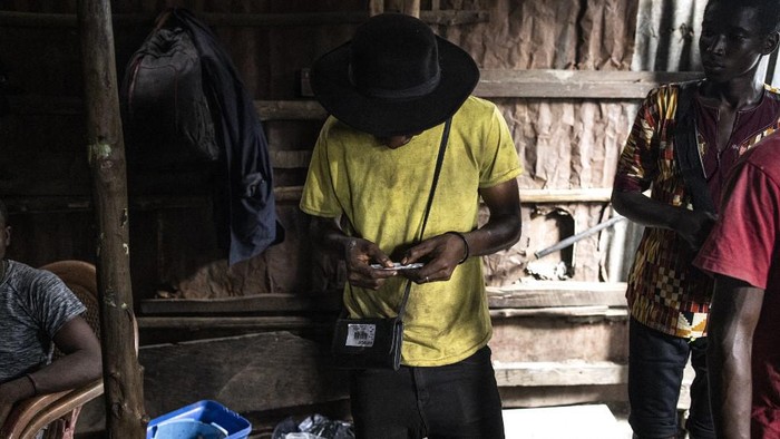 A woman holds a packet of water outside a drug den at the Kington landfill site in Freetown on June 21, 2023. In recent years Kush, a mix of various chemicals and plants that mimic the natural properties found in cannabis, according to the National Drug Agency, is increasingly being used by youth in Sierra Leone. At only 25 US cents a dose, the drug is addicting users. (Photo by JOHN WESSELS / AFP)