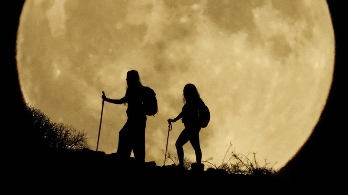 SUPERMOON-SPAIN/ Women walk up a mountain with the full moon known as the