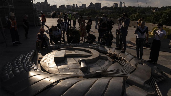 Members of the media surround a Soviet emblem removed from the shield of the Motherland Monument in Kyiv, Ukraine, Tuesday, Aug. 1, 2023. (AP Photo/Jae C. Hong)