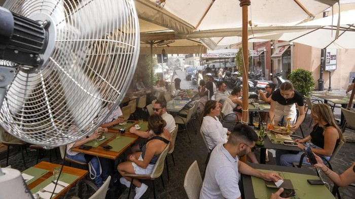 A fan sprays water to cool off customers at a restaurants in downtown Rome, Tuesday, July 25, 2023. Rising global temperatures are elevating air conditioning from a luxury to a necessity in many parts of Europe, which long has had a conflictual relationship with energy-sucking cooling systems deemed by many a U.S. indulgence. (AP Photo/Andrew Medichini)
