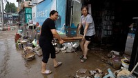 Seorang pemilik toko perlengkapan tulis mengeluarkan barang dari toko usai banjir surut.  