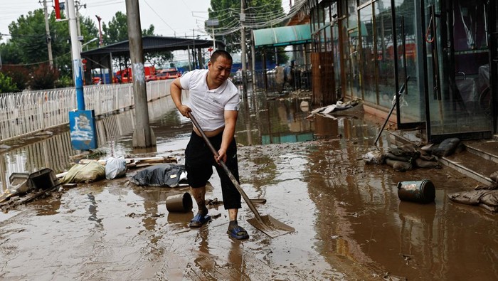 A stationary store owner moves items out of the store after remnants of Typhoon Doksuri brought rains and floods in Beijing, China August 2, 2023. REUTERS/Tingshu Wang