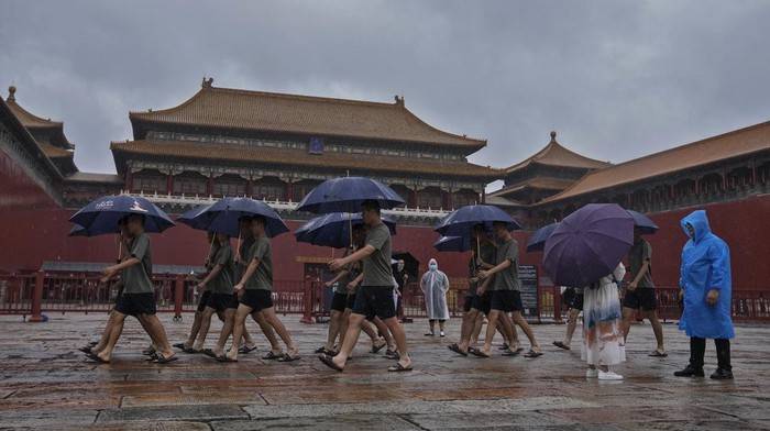 Curah Hujan di Beijing Catat Rekor, Paling Deras dalam 140 Tahun Terakhir People's Liberation Army (PLA) soldiers carrying umbrellas march past visitors at the closed Forbidden City as a rainstorm soak Beijing, Sunday, July 30, 2023. Forbidden City and other tourist destinations in the capital city was ordered to close after authorities issued a red alert for rainstorms, as heavy rains brought by Typhoon Doksuri are expected to pound the Chinese capital and vast areas in the north. (AP Photo/Andy Wong)