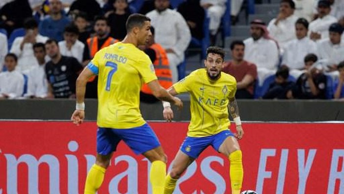 Nassrs Portuguese forward Cristiano Ronaldo (L) looks on as Nassrs Brazilian defender Alex Telles runs with the ball during the 2023 Arab Club Champions Cup group C football match between Saudi Arabias Al-Nassr and Saudi Arabias Al-Shabab at the King Fahd Stadium in Taif on July 28, 2023. (Photo by AFP)