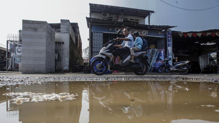 Pengendara sepeda motor melintasi jalan yang rusak dan berlubang di Jalan Sirojul Munir, Nanggewer, Cibinong, Kabupaten Bogor, Jawa Barat, Kamis (3/8/2023). Jalan yang merupakan salah satu akses menuju kawasan Pemerintahan Kabupaten Bogor tersebut rusak selama berbulan-bulan dan dan belum diperbaiki. ANTARA FOTO/Yulius Satria Wijaya/rwa.