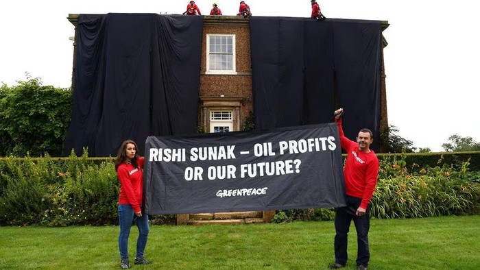 Greenpeace activists hold a banner while others cover British Prime Minister Rishi Sunaks £2m manor house in oil-black fabric in protest of his backing for a major expansion of North Sea oil and gas drilling amidst a summer of escalating climate impacts, in Yorkshire, Britain August 3, 2023. Greenpeace/Handout via REUTERS