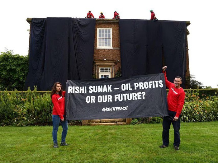 Greenpeace activists hold a banner while others cover British Prime Minister Rishi Sunaks £2m manor house in oil-black fabric in protest of his backing for a major expansion of North Sea oil and gas drilling amidst a summer of escalating climate impacts, in Yorkshire, Britain August 3, 2023. Greenpeace/Handout via REUTERS