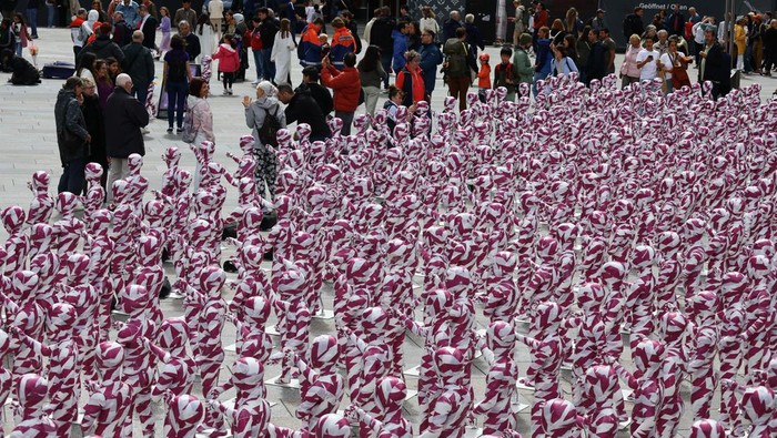 A view of children mannequins wrapped in purple and white barricade tape placed in front of the Cologne Cathedral, installed there by German artist Dennis Josef Meseg, called 