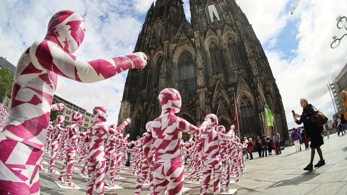 Instalasi Seni Jadi Bentuk Protes Skandal Pelecehan di Katedral Jerman A view of children mannequins wrapped in purple and white barricade tape placed in front of the Cologne Cathedral, installed there by German artist Dennis Josef Meseg, called