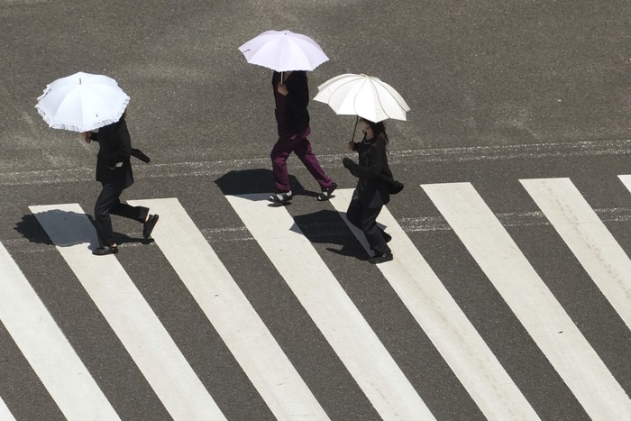 People cross a street in scorching heat at Ginza district in Tokyo, Japan, Friday, Aug. 4, 2023. Hot weather continues in the metro area as temperatures rise higher than 36 degrees Celsius (96.8 degrees Fahrenheit), according to Japans meteorological bureau. (AP Photo/Shuji Kajiyama)