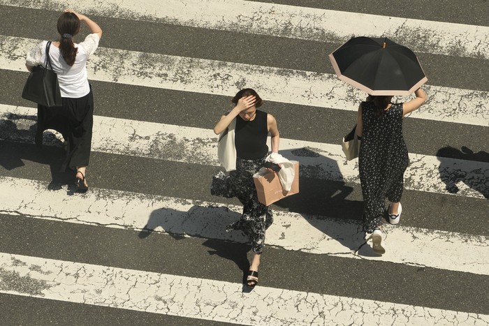 People cross a street in scorching heat at Ginza district in Tokyo, Japan, Friday, Aug. 4, 2023. Hot weather continues in the metro area as temperatures rise higher than 36 degrees Celsius (96.8 degrees Fahrenheit), according to Japans meteorological bureau. (AP Photo/Shuji Kajiyama)