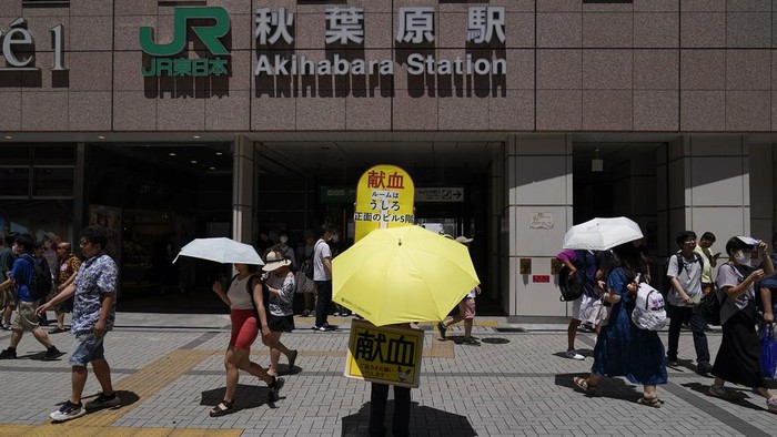 People cross a street in scorching heat at Ginza district in Tokyo, Japan, Friday, Aug. 4, 2023. Hot weather continues in the metro area as temperatures rise higher than 36 degrees Celsius (96.8 degrees Fahrenheit), according to Japan's meteorological bureau. (AP Photo/Shuji Kajiyama)