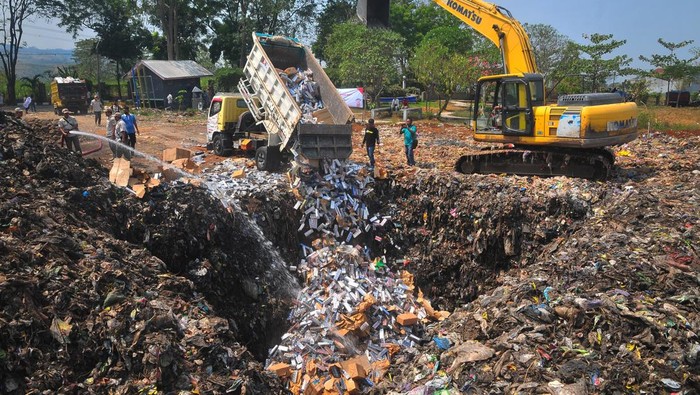 Petugas menggunakan alat berat untuk memusnahkan rokok ilegal di Tempat Pembuangan Akhir (TPA) Tanjungrejo, Kudus, Jawa Tengah, Jumat (4/8/2023). Bea cukai bersama pemerintah setempat memusnahkan sebanyak 6,16 juta batang rokok ilegal berbagai merek hasil penindakan periode Mei 2022 sampai Mei 2023, dengan perkiraan nilai barang Rp7 miliar dan potensi kerugian negara Rp4,7 miliar. ANTARA FOTO/Yusuf Nugroho/foc.