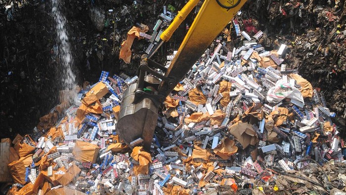 Petugas menggunakan alat berat untuk memusnahkan rokok ilegal di Tempat Pembuangan Akhir (TPA) Tanjungrejo, Kudus, Jawa Tengah, Jumat (4/8/2023). Bea cukai bersama pemerintah setempat memusnahkan sebanyak 6,16 juta batang rokok ilegal berbagai merek hasil penindakan periode Mei 2022 sampai Mei 2023, dengan perkiraan nilai barang Rp7 miliar dan potensi kerugian negara Rp4,7 miliar. ANTARA FOTO/Yusuf Nugroho/foc.