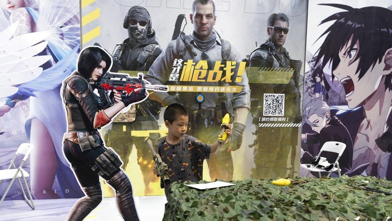 Youths look at their smartphones on the street in Beijing, Thursday, Aug. 3, 2023. China's internet watchdog has laid out regulations to curb the amount of time minors spend on their smartphones, in the latest blow to firms such as Tencent and ByteDance which run social media platforms and online games. (AP Photo/Ng Han Guan)