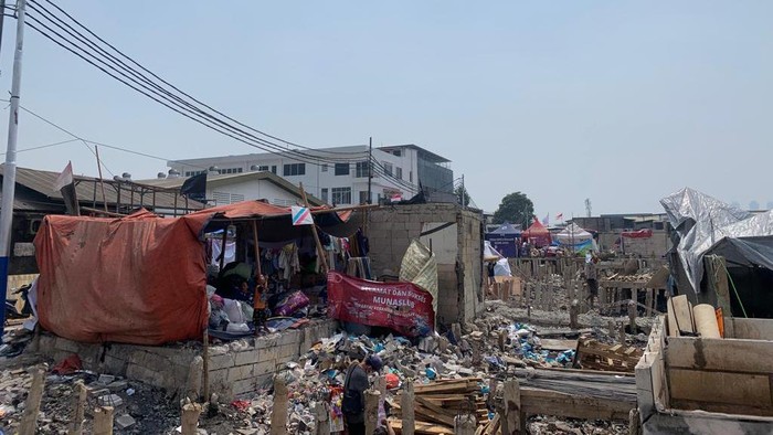 Korban kebakaran di Kapuk Muara, Jakarta Utara, mendirikan terpal di atas puing sisa bangunan yang terbakar, Sabtu (5/8/2023).