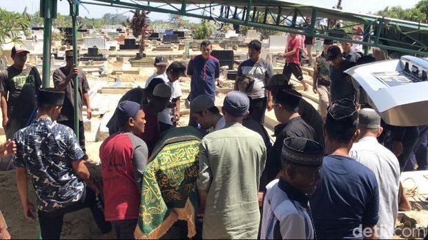 Jenazah Redho Tri Agustian saat dimasukkan ke liang lahad.